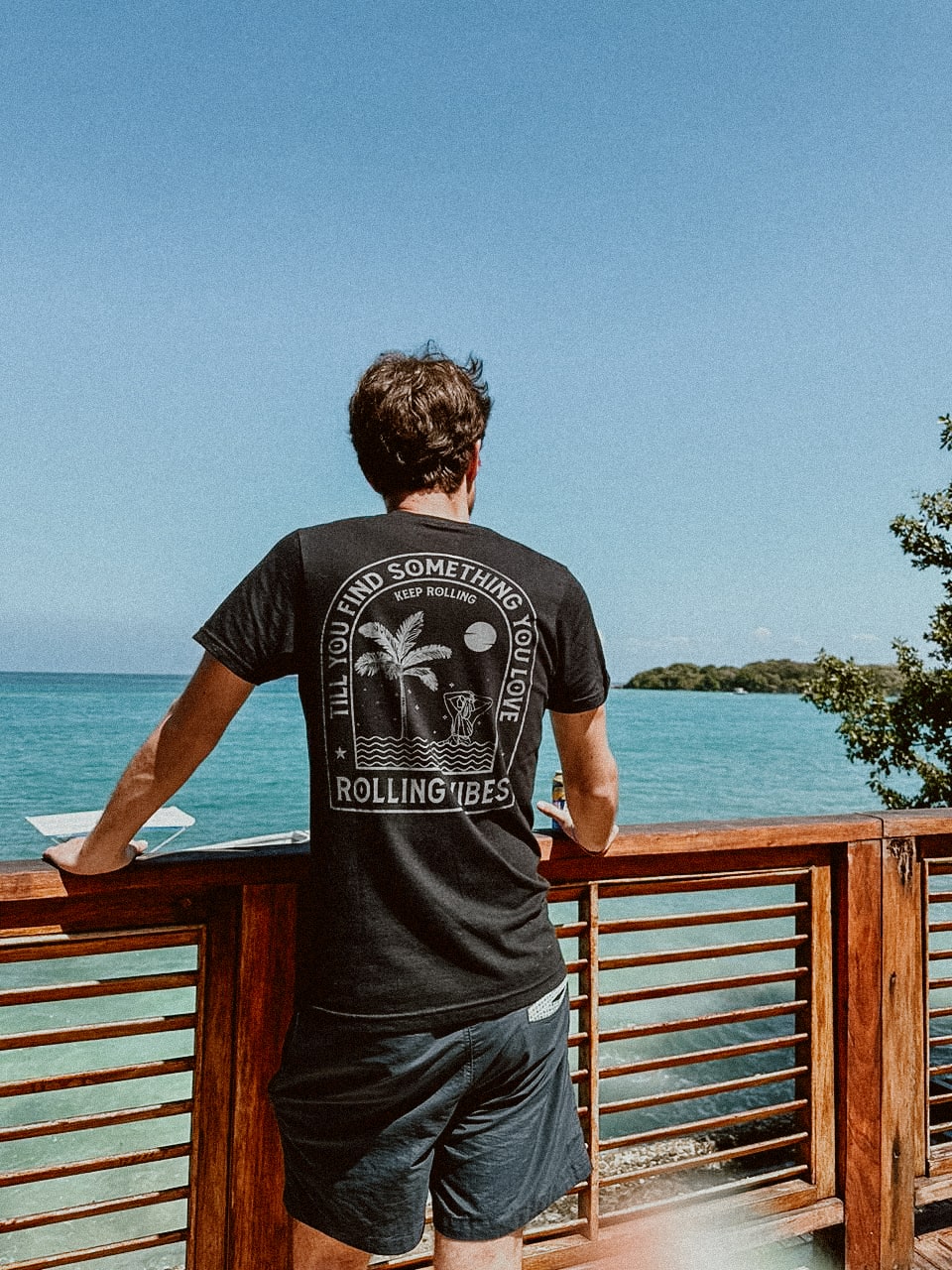 A casual tank top made of 100% cotton fabric with a relaxed fit. The design features a mermaid taking a bath surrounded by waves and palm trees on the back. The front is adorned with the Rolling Vibes logo. Perfect for a beachy, summer look.