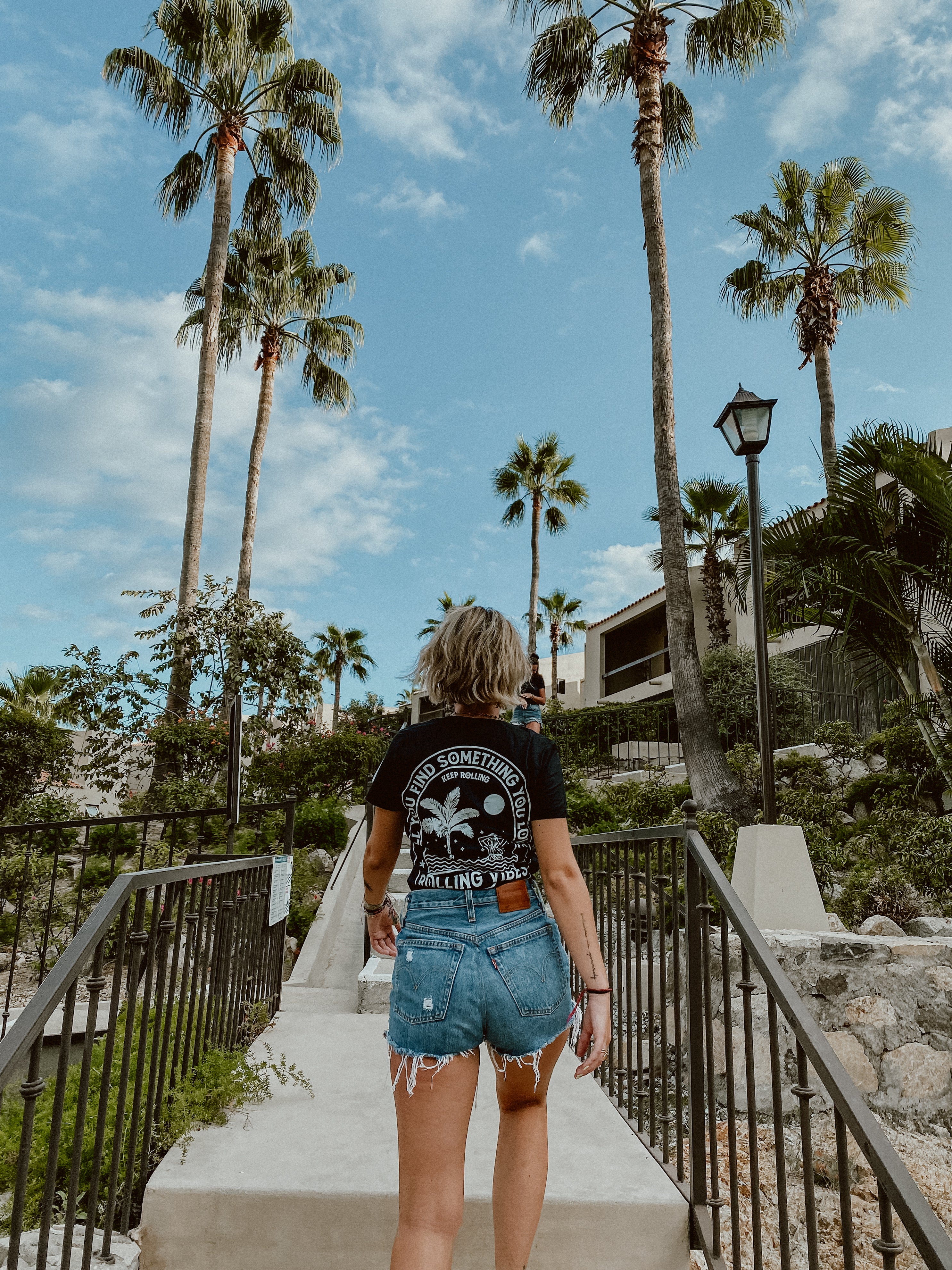 A casual tank top made of 100% cotton fabric with a relaxed fit. The design features a mermaid taking a bath surrounded by waves and palm trees on the back. The front is adorned with the Rolling Vibes logo. Perfect for a beachy, summer look.