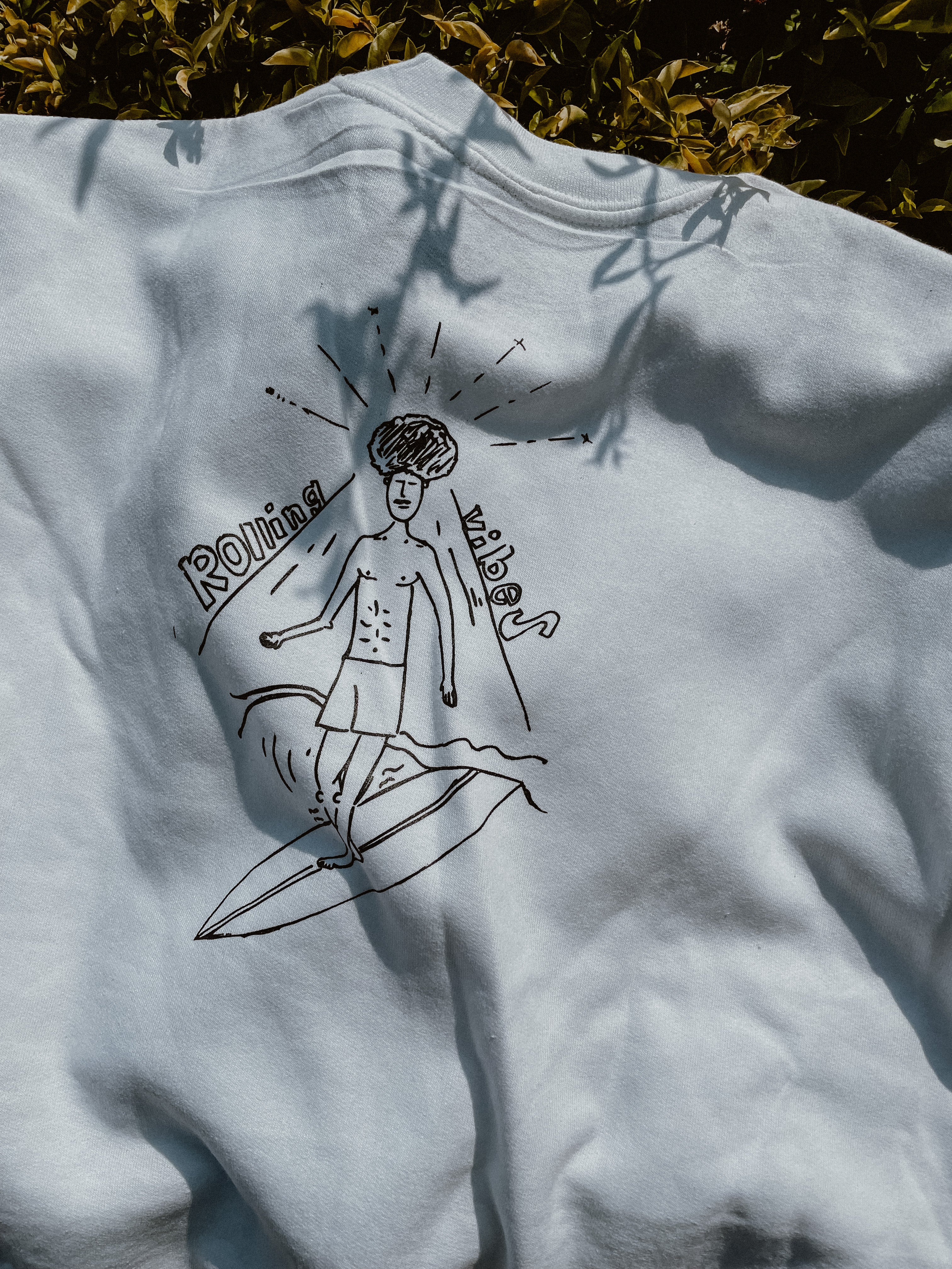 White Rolling Vibes Pullover with a drawing of a surfer with an afro on the back: "White Rolling Vibes Pullover with Surfer Design on Back